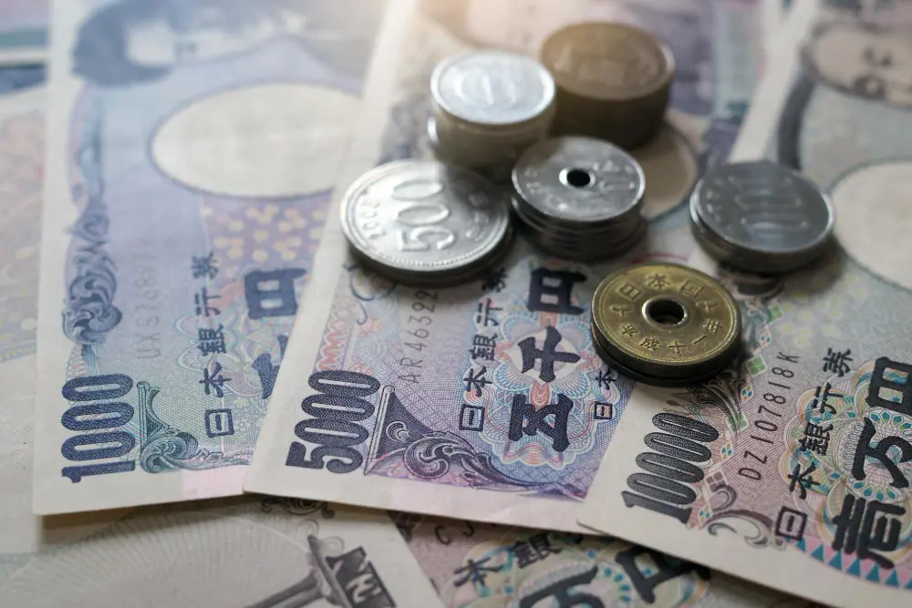 A pile of Japanese Yen including 1000, 5000, and 10000 yen notes alongside 500 and 50 yen coins, emphasizing the importance of carrying cash.