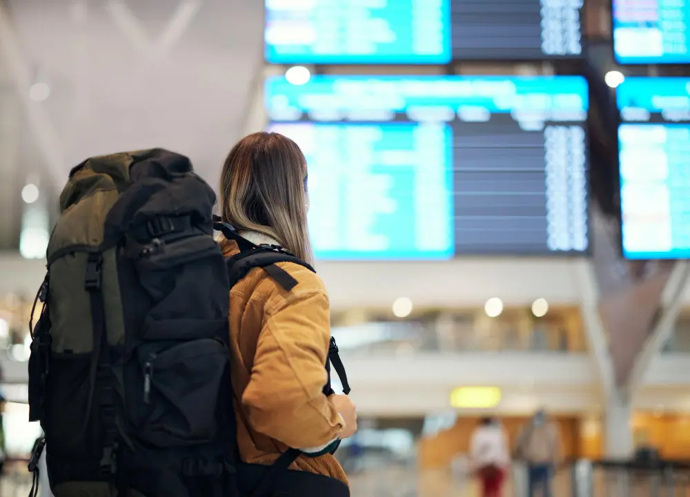 travelers sitting at an airport gate checking the time during an international flight layover