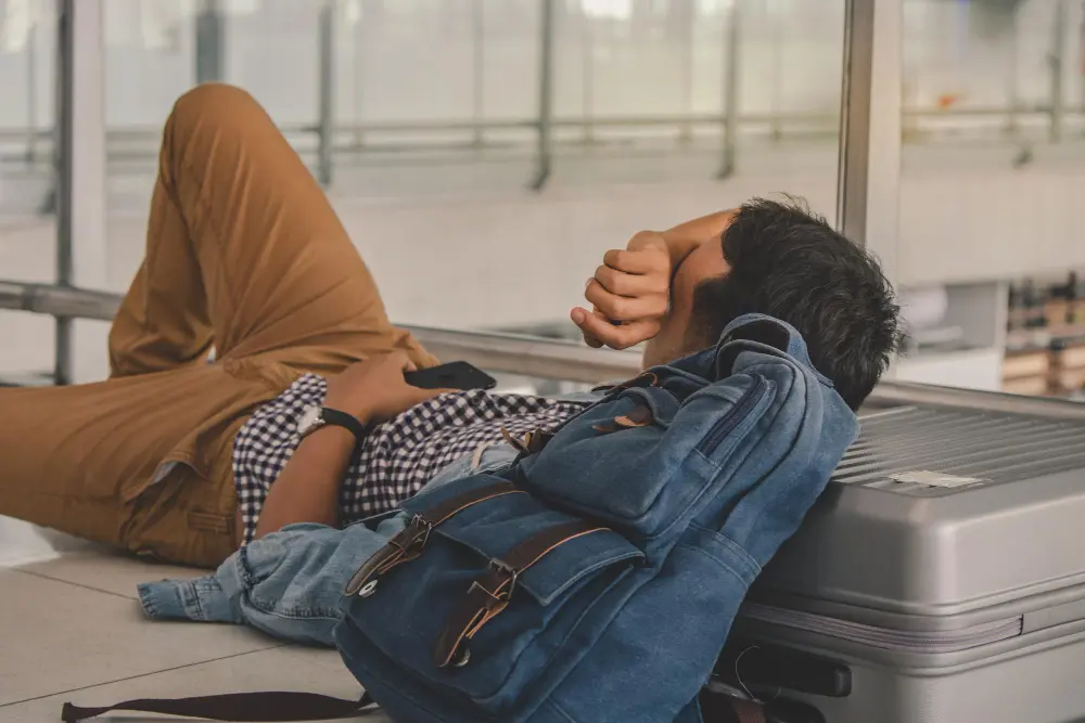 Traveler relaxing at an international airport with carry-on luggage, feeling alert and ready after managing jet lag effectively