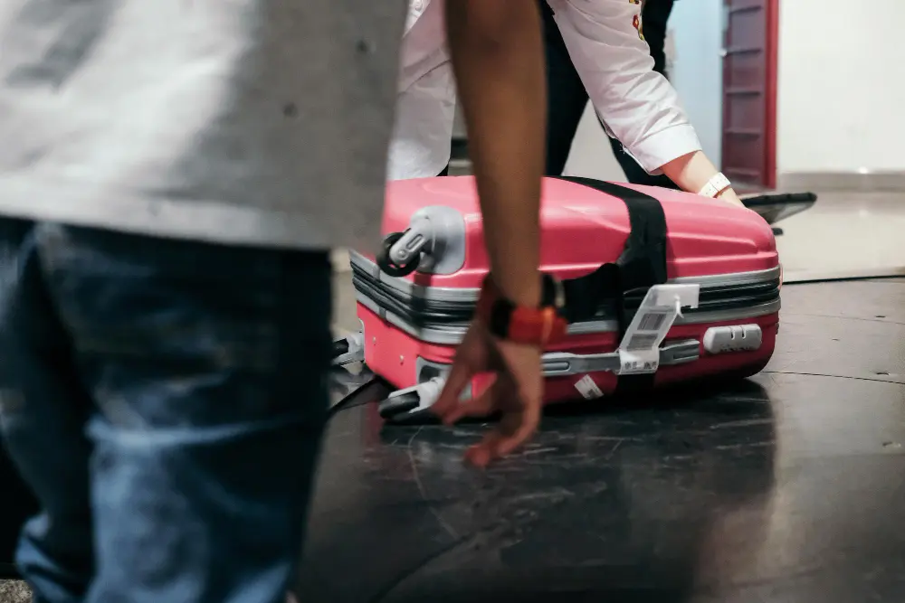 Traveler at airport baggage claim looking concerned at damaged suitcase after international flight