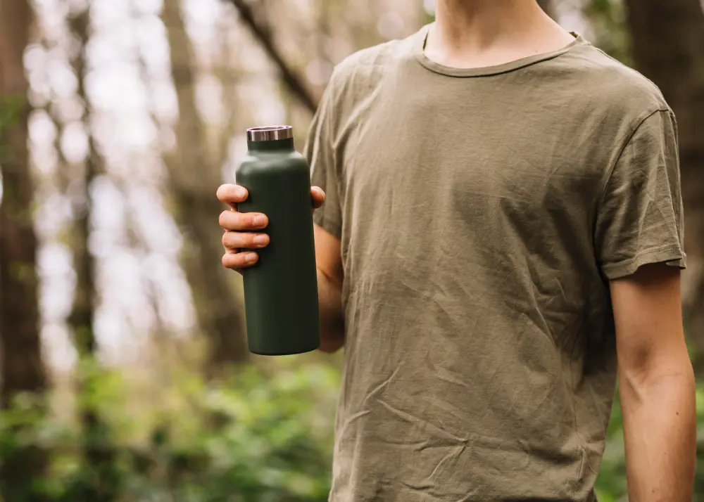 Traveler using a reusable water bottle while sightseeing, promoting eco-friendly and budget-friendly travel habits