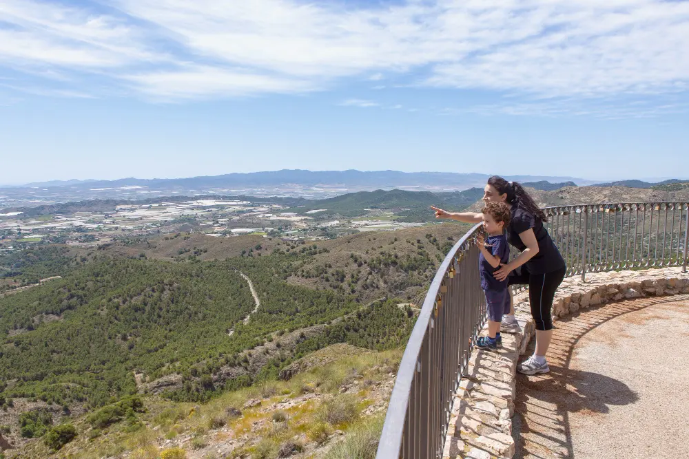 Travelers standing at a mountain scenic overlook during golden hour, one of the most memorable road stops on a road trip