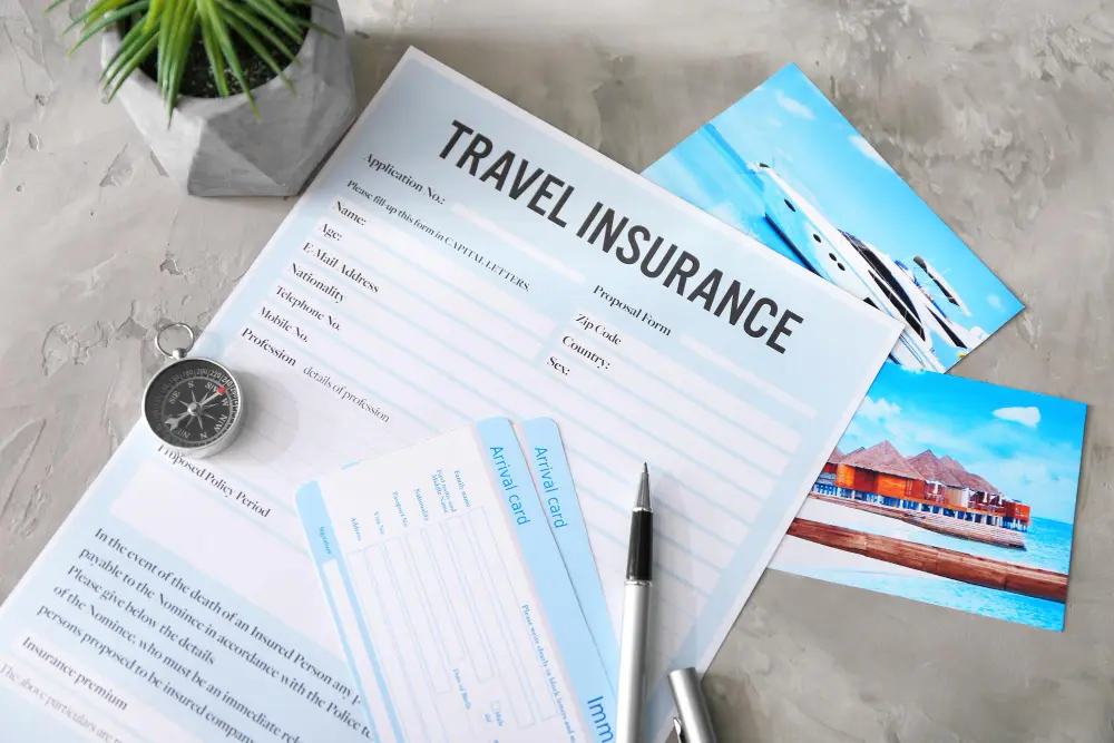 Traveler comparing travel insurance options on laptop with passport, boarding pass, and suitcase on table before international trip