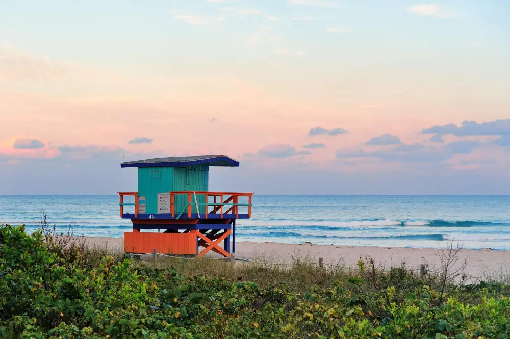 Cocoa Beach Florida pier extending into Atlantic Ocean with families surfing and enjoying beach activities, showcasing affordable Space Coast spring break destinations for families on a budget