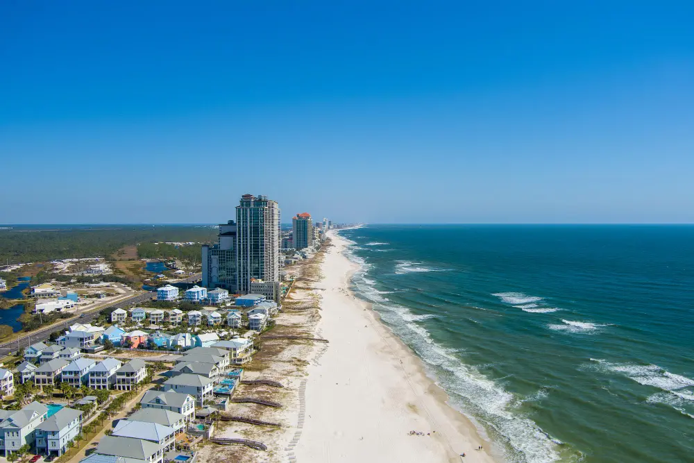 Gulf Shores Alabama white sand beach with emerald waters and families relaxing, representing affordable Gulf Coast spring break destinations for families on a budget