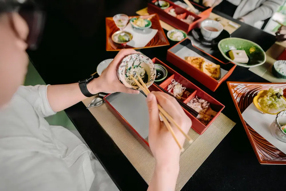 A delicious bowl of traditional ramen and colorful sushi rolls on a wooden table, showing the food variety when planning how much to travel japan.