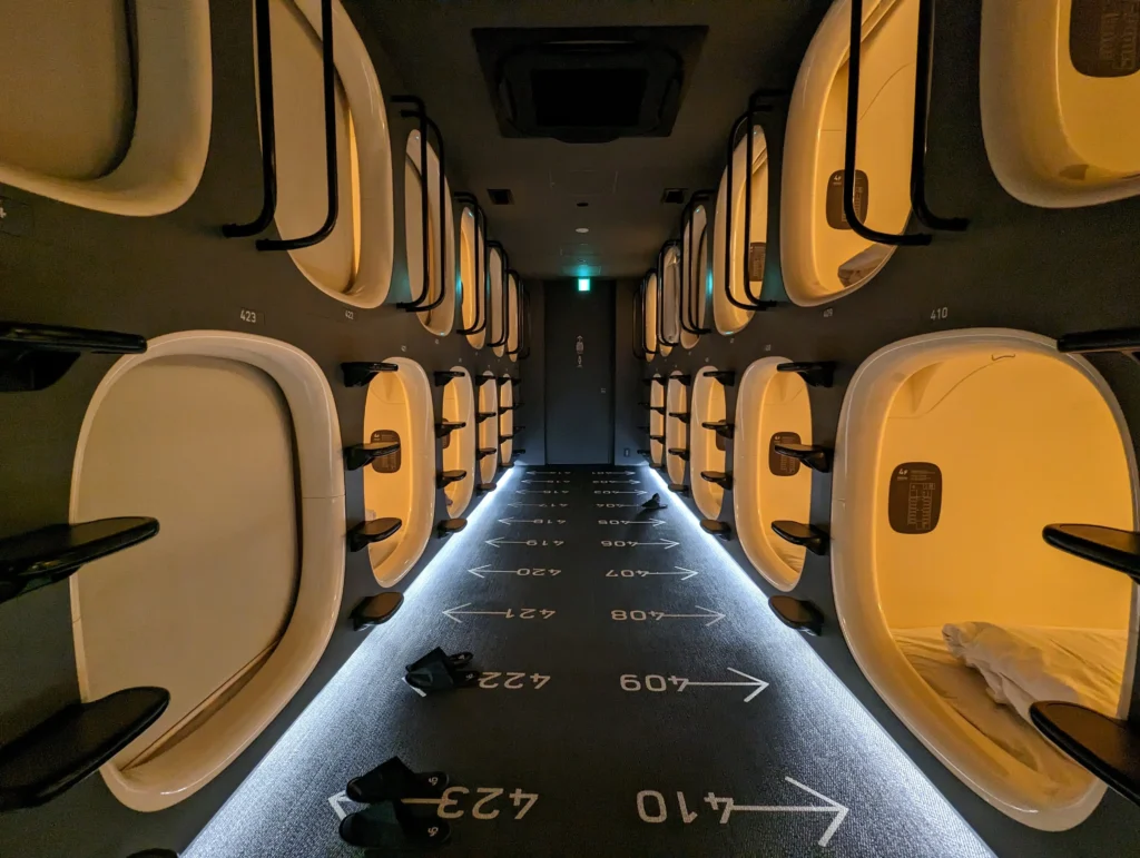 A split image showing a traditional Japanese ryokan room with tatami mats on one side and a modern capsule hotel pod on the other, comparing lodging options when figuring out how much to travel to japan.