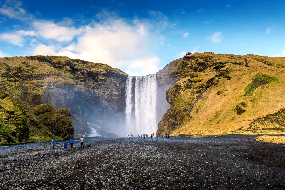 A traveler looking at a waterfall in Iceland, illustrating how to plan a trip to Iceland across different seasons.